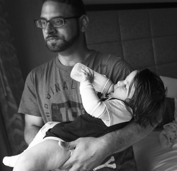 Father holding baby drinking from bottle.