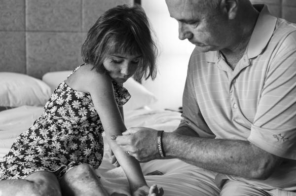 This photo is of a father applying a bandage to his daughter's elbow.