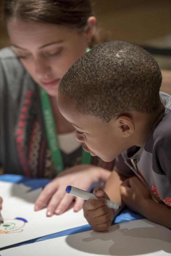 This photo is of a volunteer coloring with a young boy.